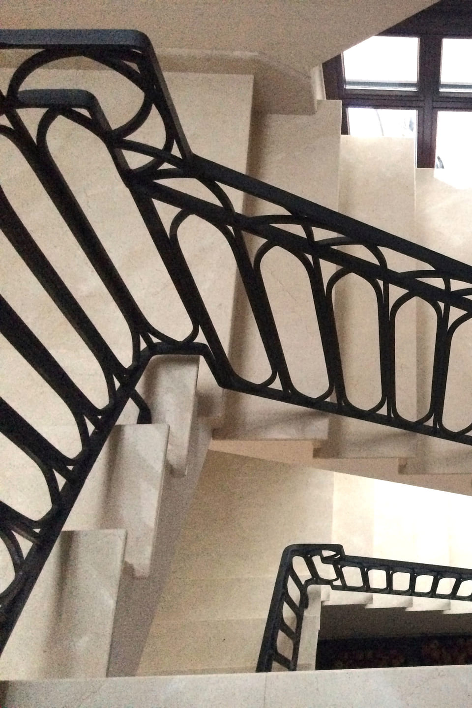 Marmurowe schody przy oknie z kutą balustradą, widok z dołu